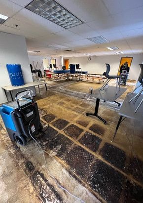 A large room with tables and chairs and a vacuum cleaner in it.