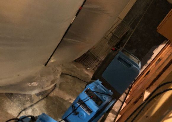 A blue machine is sitting in a room next to a white tarp.