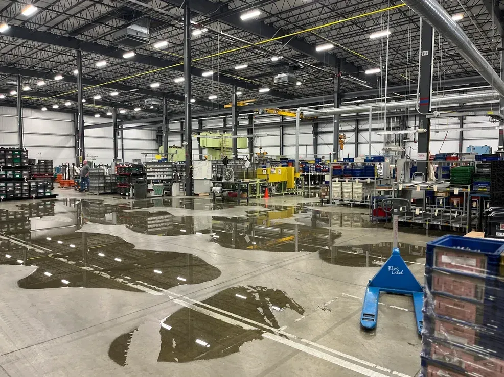 A large warehouse with a lot of water on the floor.