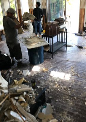 A man is standing in a messy room holding a piece of paper