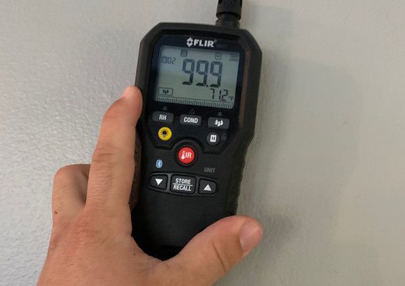 A person is holding a digital thermometer in their hand.