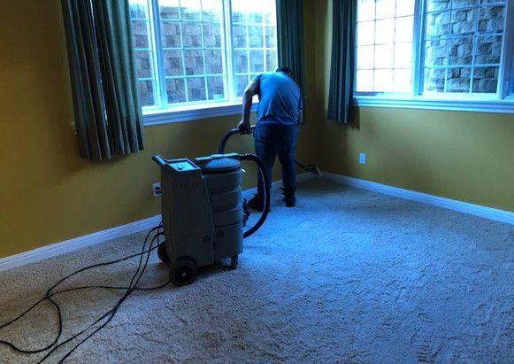 A man is using a vacuum cleaner to clean a carpet in a room.
