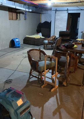 A basement filled with furniture and a vacuum cleaner.