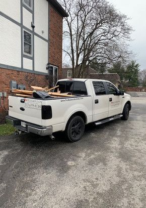 A white pickup truck is parked in front of a brick building.