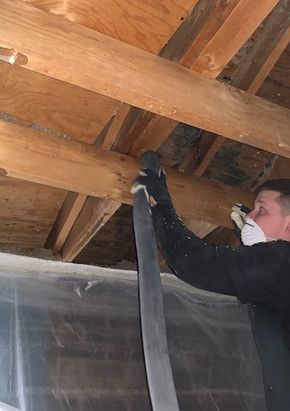 A man is wearing a mask and gloves while working on a wooden ceiling.