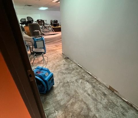 A hallway with chairs and a blue bag on the floor.