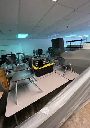 A room filled with tables and chairs covered in plastic.