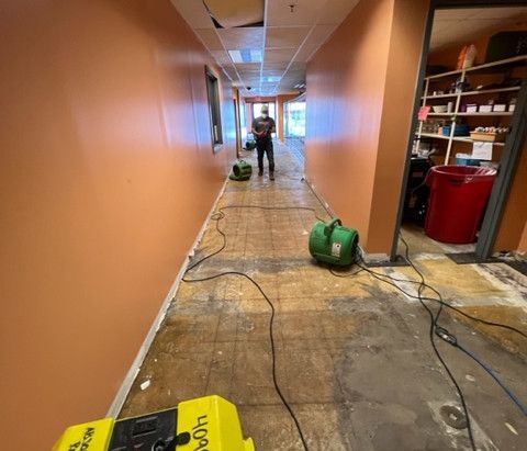 A man is standing in a hallway next to a vacuum cleaner.