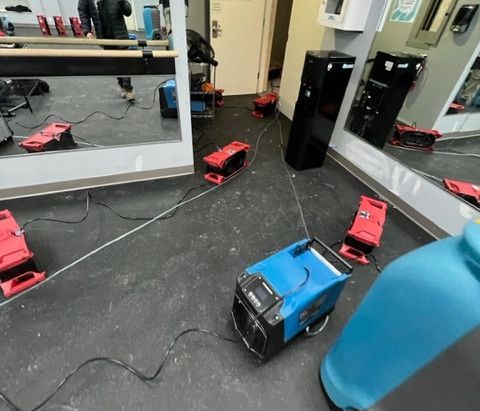 A blue and red machine is sitting on the floor of a gym.