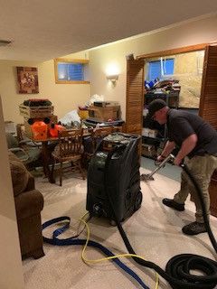 A man is using a vacuum cleaner to clean a carpet in a living room.