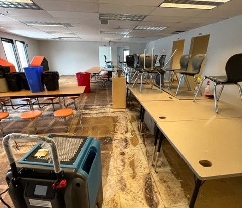 A room with tables and chairs and a vacuum cleaner