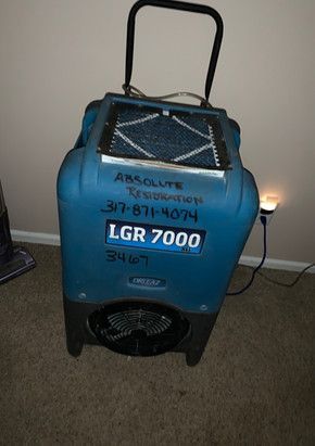 A blue dryer is sitting on a carpet in a room.