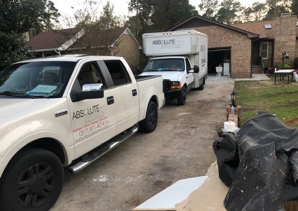 Two white trucks are parked in front of a house.
