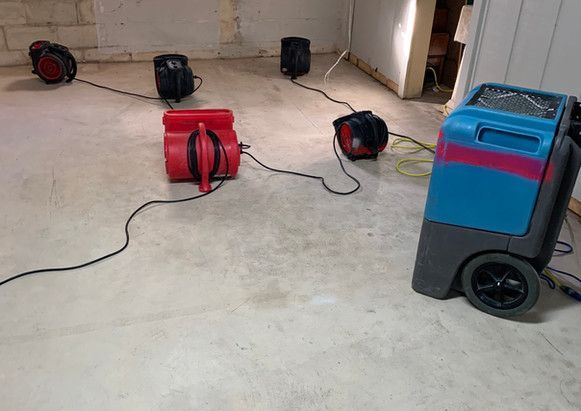 A bunch of vacuum cleaners are sitting on the floor in a room.