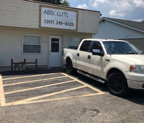 A white truck is parked in a parking lot in front of a building.