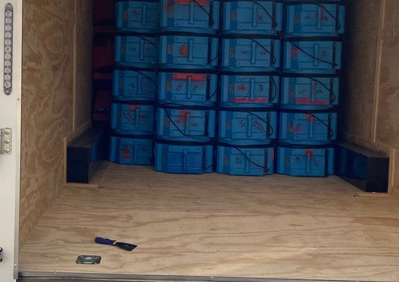 The inside of a trailer filled with blue crates.