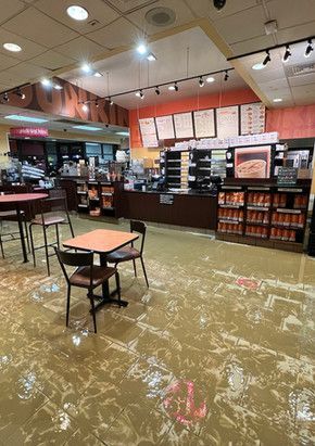 A flooded restaurant with tables and chairs and a counter.