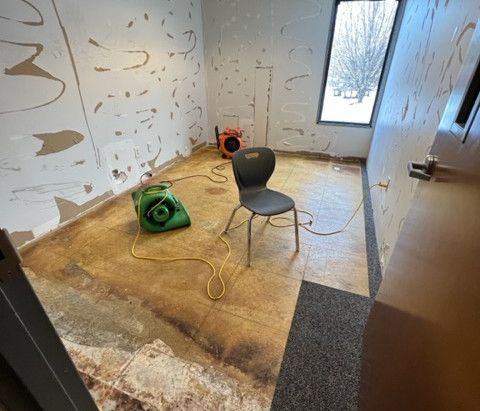 A room with a chair and a green fan on the floor.