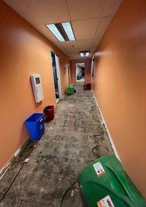 A long hallway with orange walls and a green vacuum cleaner on the floor.