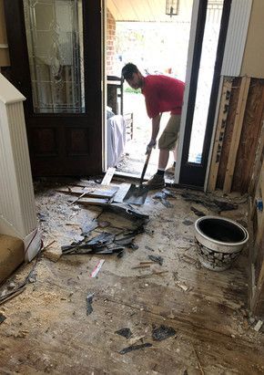 A man is cleaning the floor of a house with a shovel.