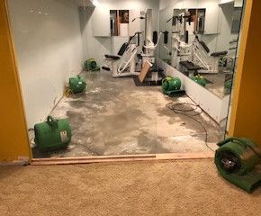 A gym with a lot of equipment and a lot of water on the floor.