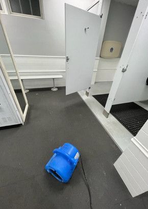 A blue vacuum cleaner is sitting on the floor in a locker room.