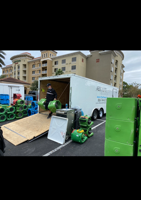 A man is loading equipment into a trailer in a parking lot.