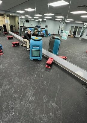 A man is sitting on a bench in a gym next to a machine.