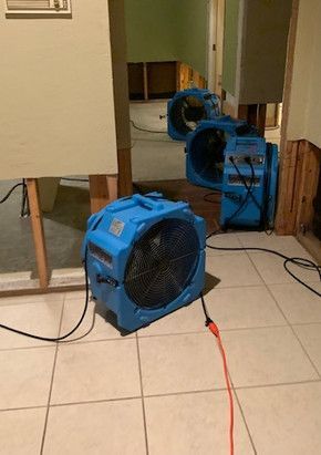 Two blue fans are sitting on a tiled floor in a room.