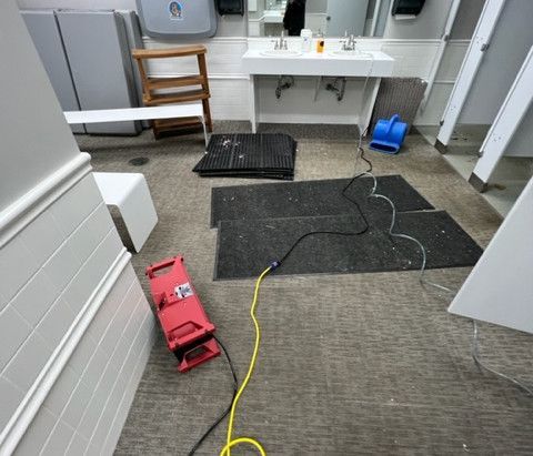 A bathroom with a sink and a fan on the floor.