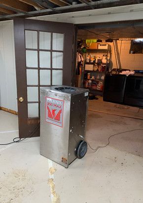 A machine is sitting in a basement next to a door.