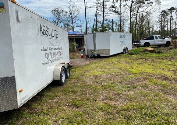 Two trailers are parked in a grassy field next to a truck.