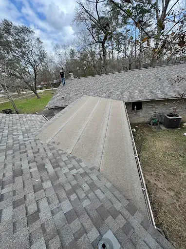 Person on a roof inspecting shingles on a cloudy day.