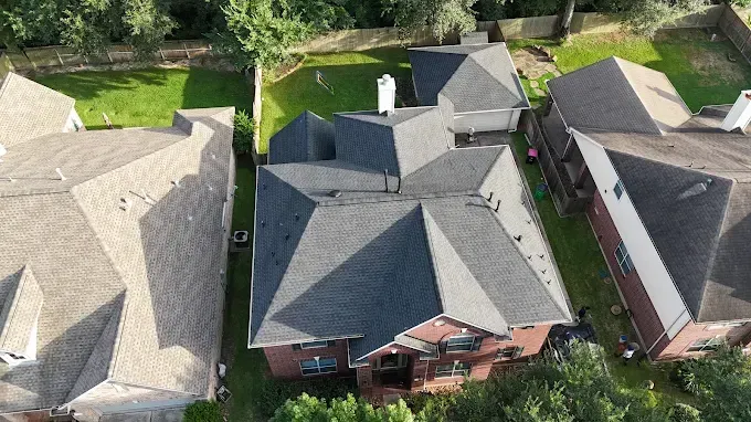 Aerial view of several houses with dark gray roofs and green lawns.