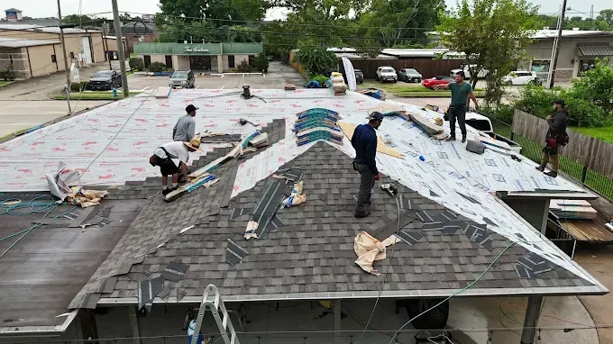 Construction workers on a roof, replacing shingles.