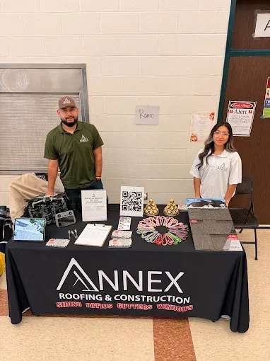 Two people stand behind a black table with