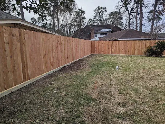 Wooden fence enclosing a grassy backyard.