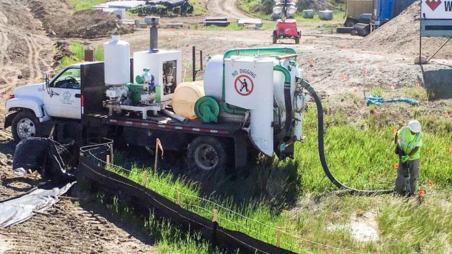 hydrovacing vehicle outdoors with worker pumping water out of ground