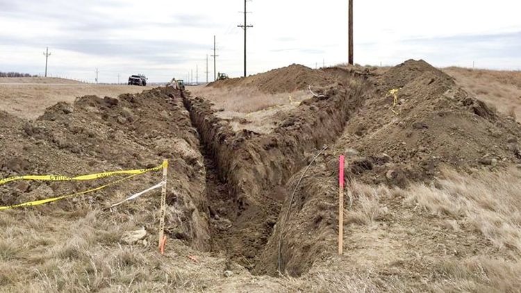 ditch with piles of dirt and caution tape around