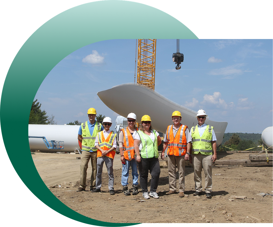 A group of Civil 1 engineers are posing for a picture in front of a wind turbine.