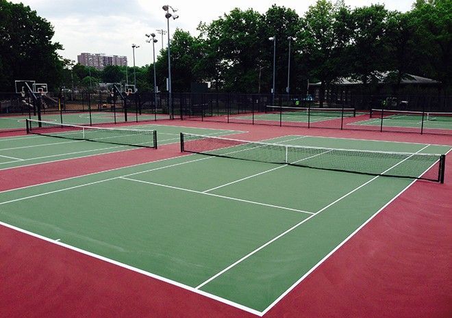 A green and red tennis court with trees in the background
