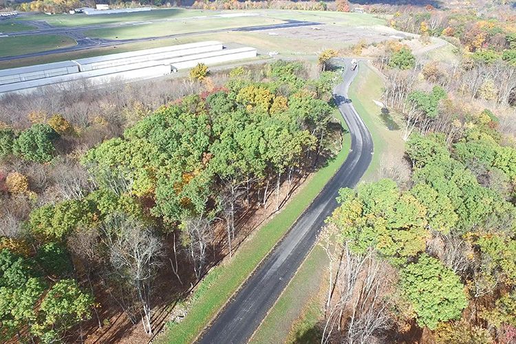 An aerial view of a road going through a forest.