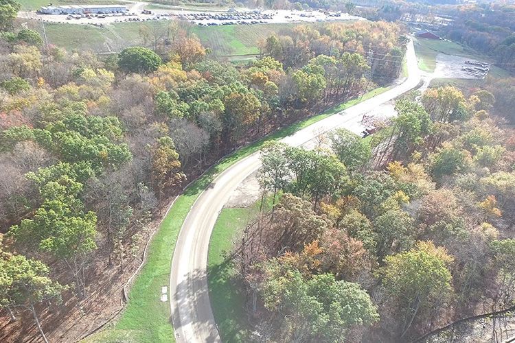 An aerial view of a curvy road surrounded by trees and grass.