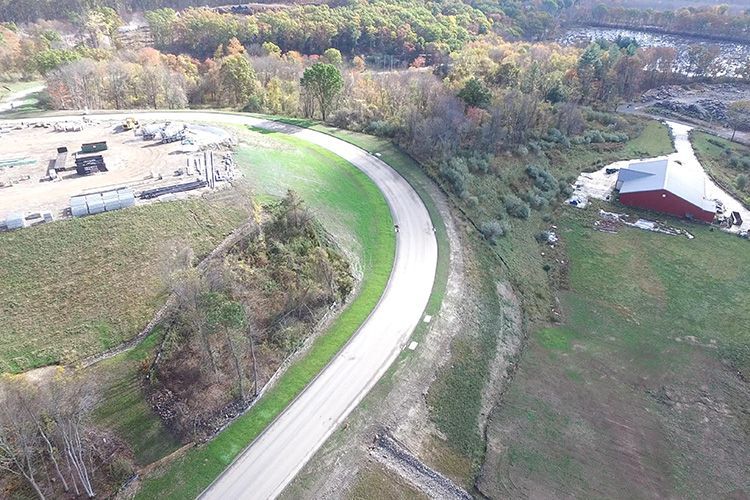 An aerial view of a curvy road surrounded by trees and grass.