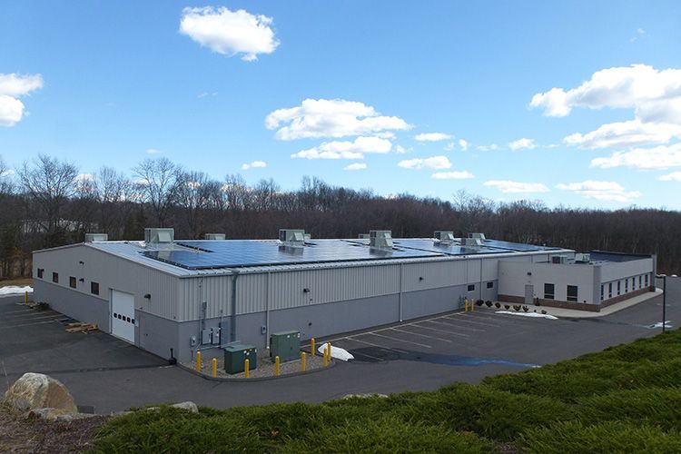An aerial view of a large industrial building with solar panels on the roof.