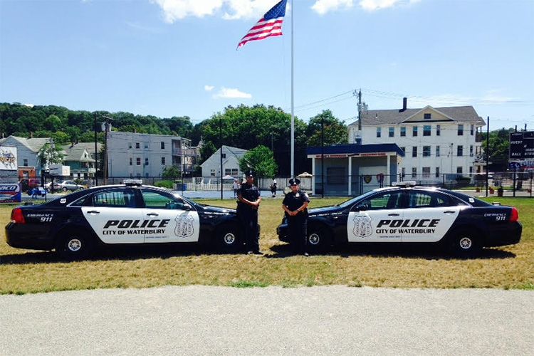 Two police officers standing next to two police cars