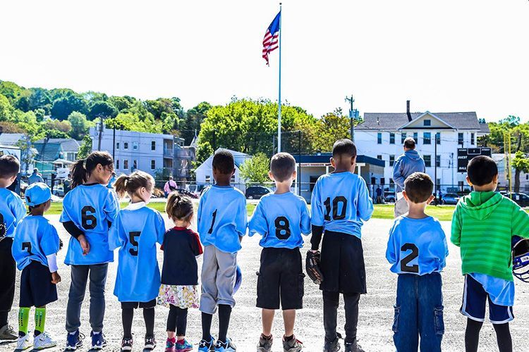 A group of children are standing in front of an american flag