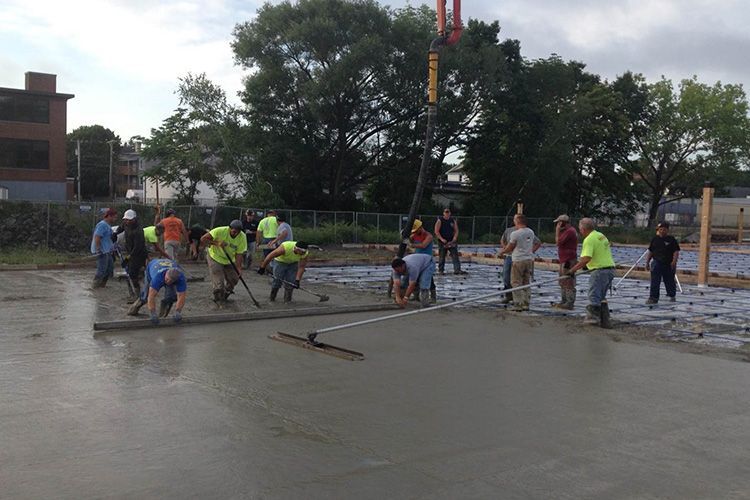 A group of construction workers are working on a concrete floor.