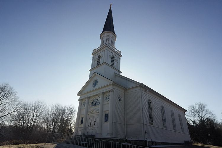 A white church with a steeple and a cross on top