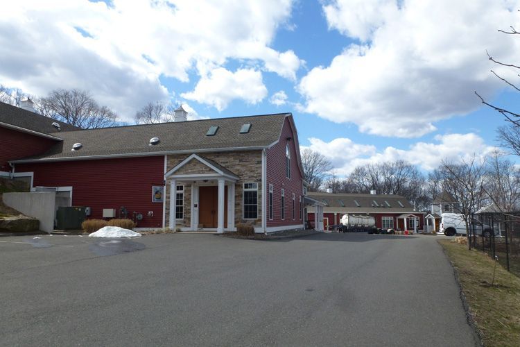A red building with a gray roof and a driveway in front of it